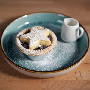 mince pie on a plate with a small jug of cream