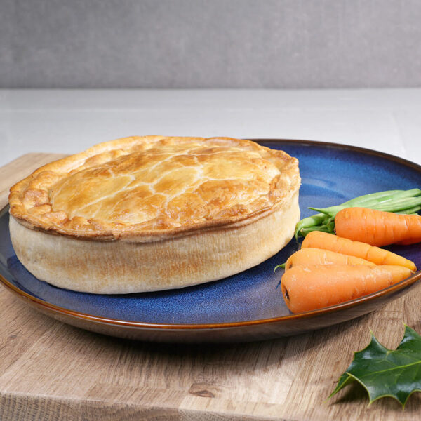 turkey, bacon & staffing large family pie on a plate with carrots and beans